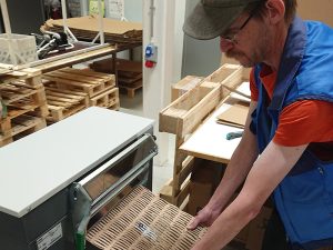 Mies valmistaa kartonkisilppurilla pakkauspehmustetta käytetyistä pahvilaatikoista.