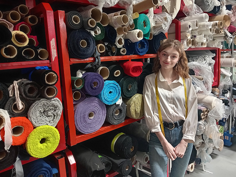 Katariina Juoperi kangasrullien vierellä TITRYn ompelimossa.